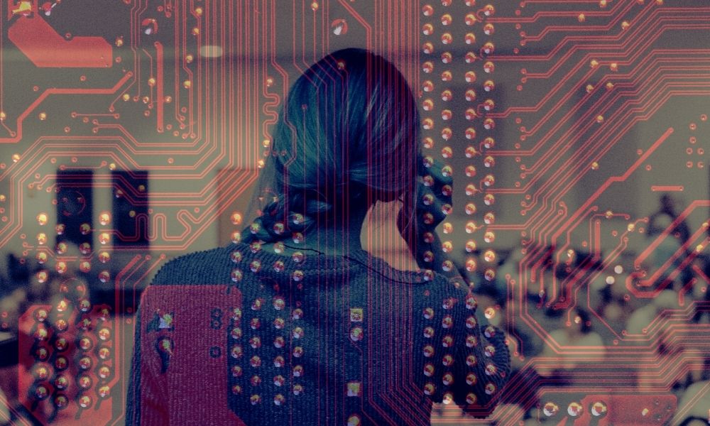woman standing in front of a lecture hall with her back to the camera with the image of a circuit board superimposed on the photograph