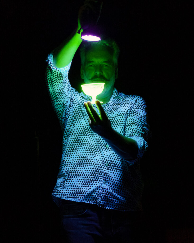 A person in the dark at the Cabaret of Dangerous Ideas, shining a flashlight onto a cup-like object in their hand.
