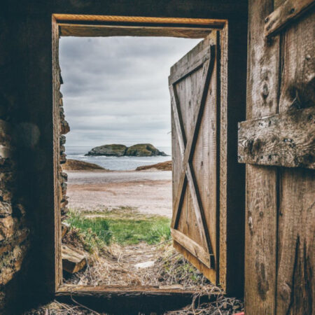 An open wooden door looking out onto a bay